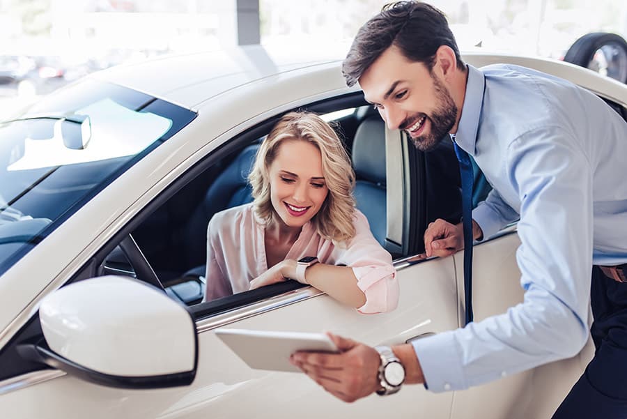Woman inside car talking to car salesman